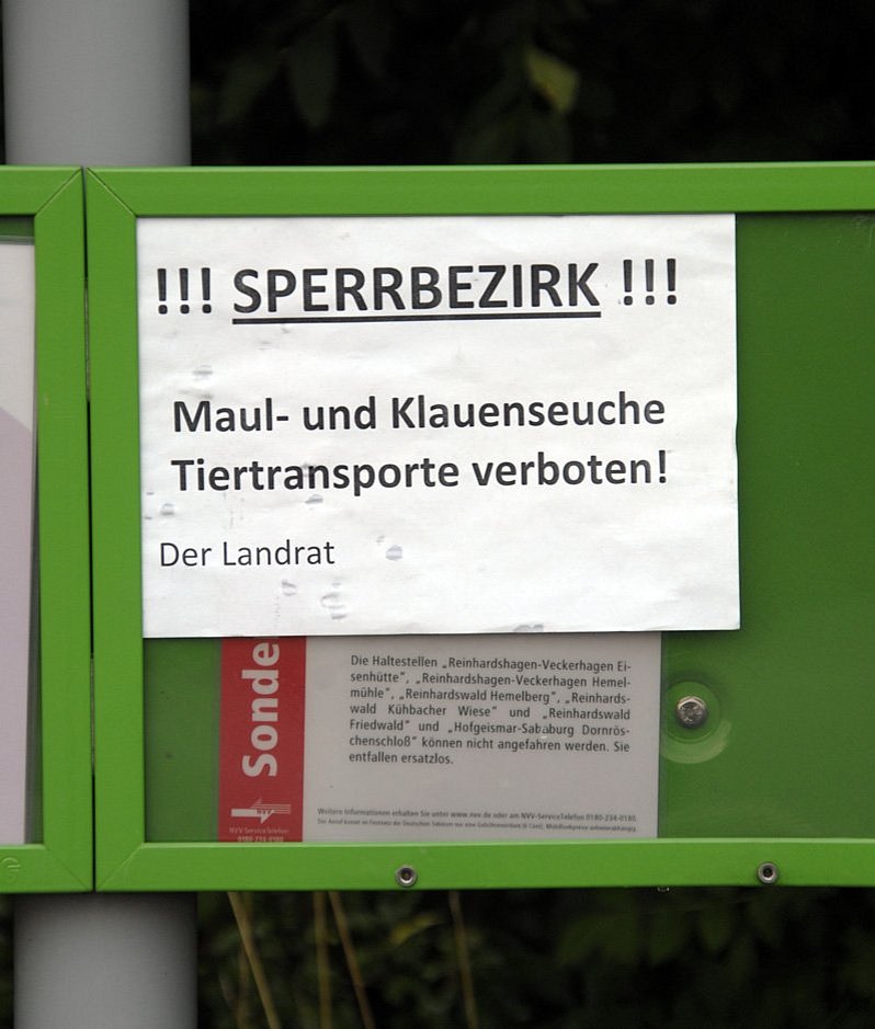 Schild mit der Aufschrift Sperrbezirk Maul- und Klauenseuche Tiertransport verboten. Klick führt zu Großansicht im neuen Fenster.