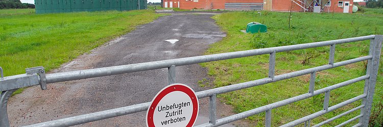Stallanlage mit Biogas-Fermenter eines Schweinebetriebs, im Vordergrund ein Schild "Unbefugten Zutritt verboten" und ein Zaun